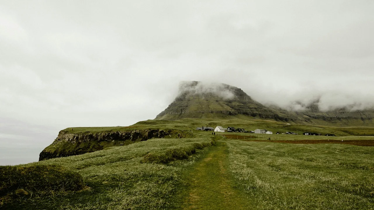 green grassland across clouded mountain