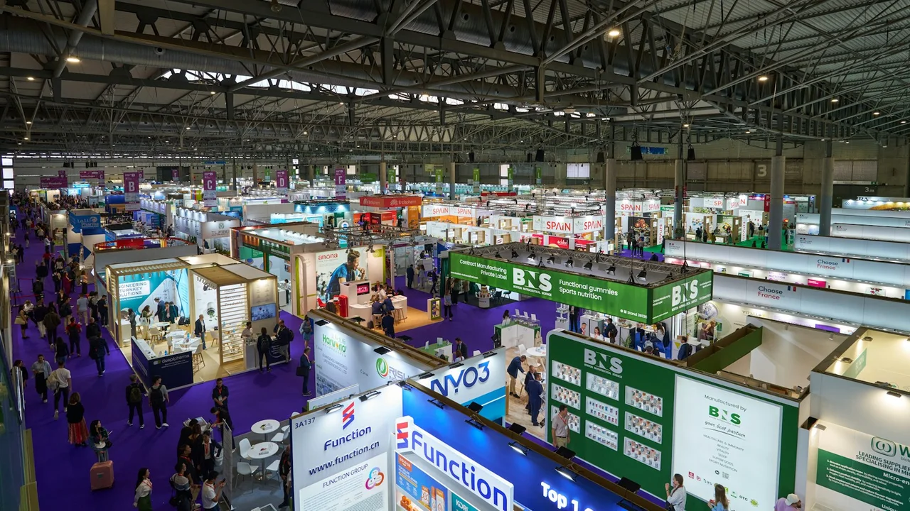 An indoor trade exhibition with vendors and visitors, photographed at Vitafoods Europe 2025 in Barcelona; illustrative, not the Canton Fair.