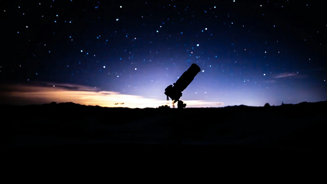a telescope sitting on top of a hill under a night sky